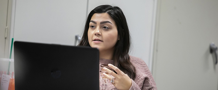 Student sitting at classroom desk speaking